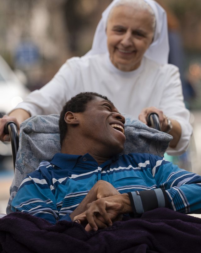 Una religiosa empuja la silla de ruedas de un joven sonriente