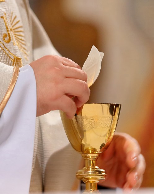 Un sacerdote alza la hostia sobre el cáliz