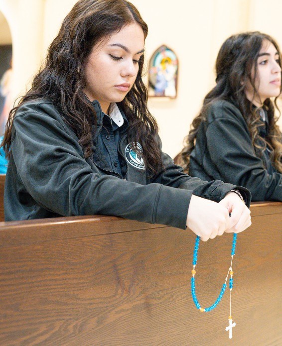 Dos jóvenes rezan el rosario en un banco de la iglesia