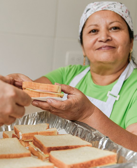 Una voluntaria reparte bocadillos en un comedor